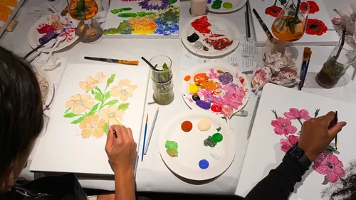 People painting flowers at a table.