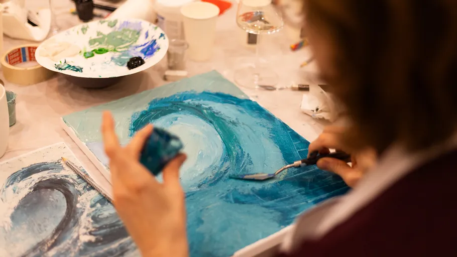 Person painting ocean waves on canvas.