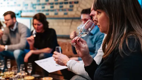 Menschen verkosten Wein in gemütlicher Umgebung.