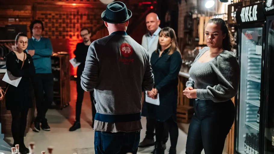 Person speaks to attentive group in bar.