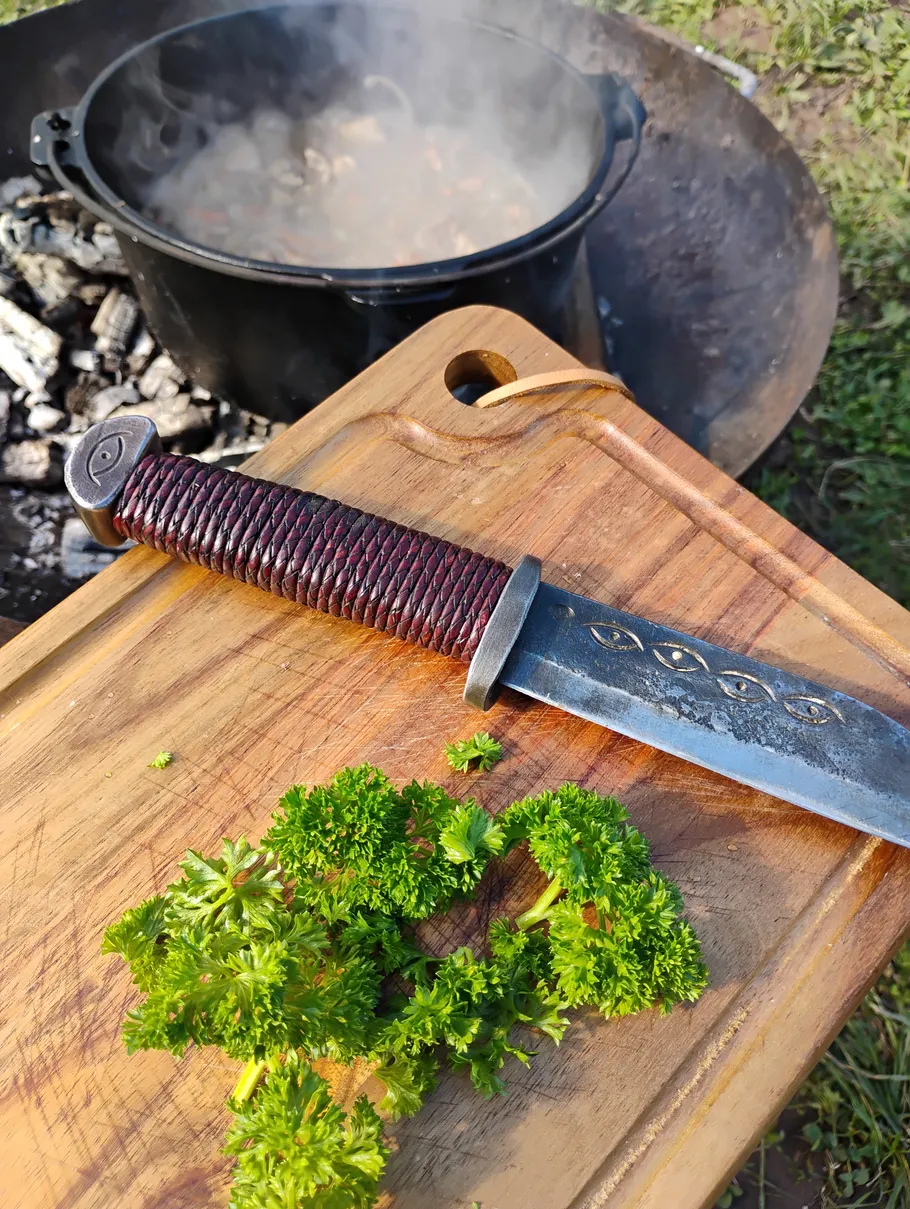 Knife and parsley on cutting board outdoors.