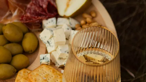 Charcuterie board with cheese, olives, and wine.