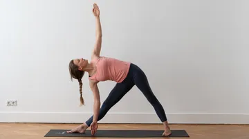 Woman practicing yoga on a mat indoors.