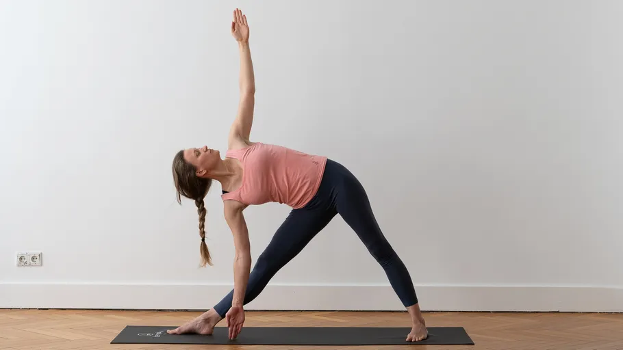 Frau praktiziert Yoga auf einer Matte innen.