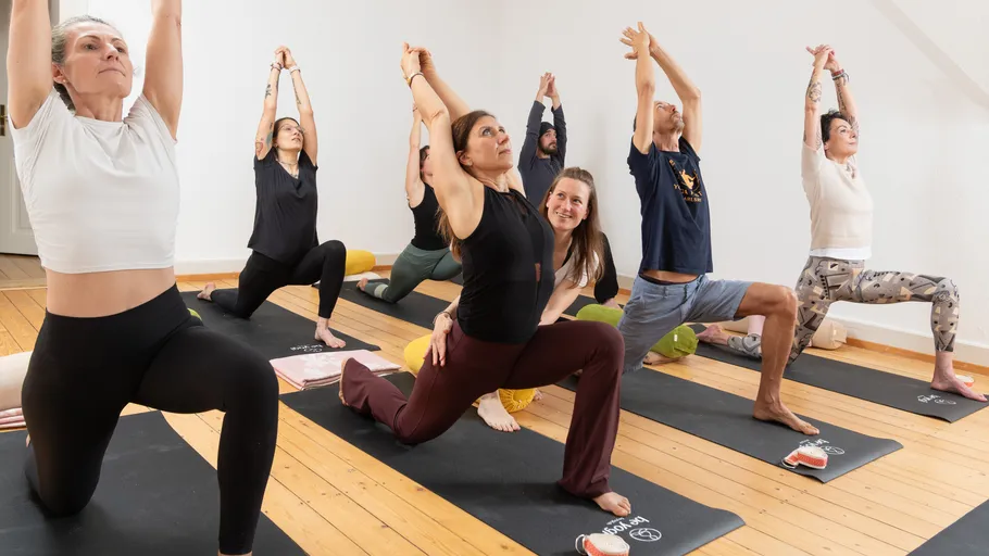 People doing yoga on mats indoors.