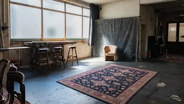 Empty studio with a chair and rug.