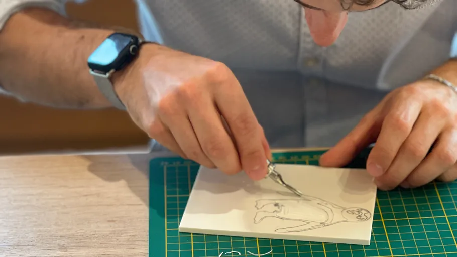 Person carving drawing with a scalpel.