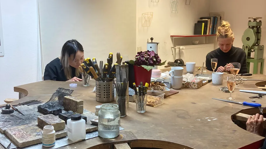 Zwei Frauen fertigen Schmuck an einem Werktisch.