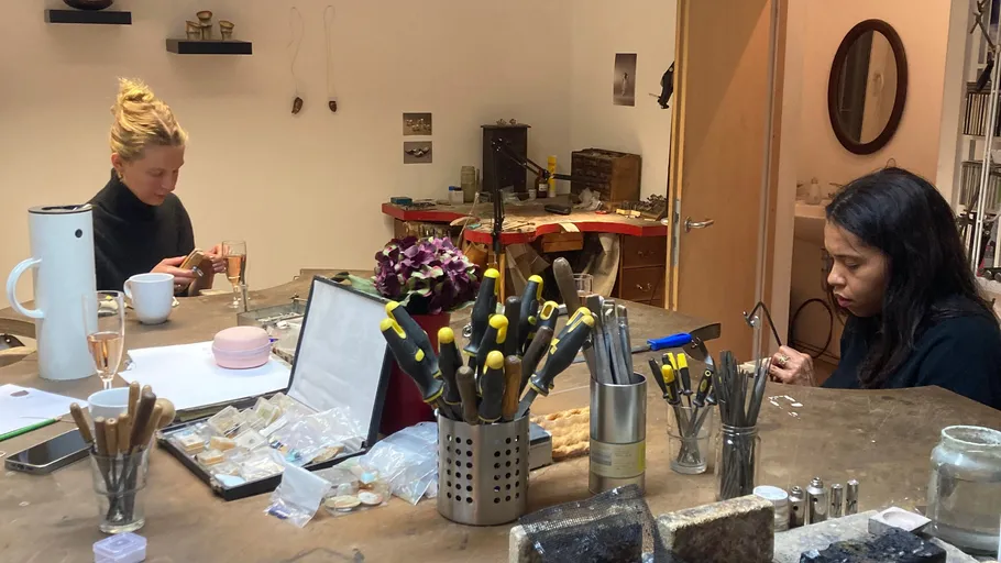 Two women crafting jewelry in workshop.