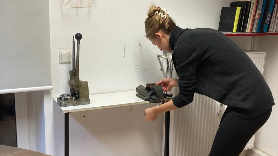 Person using vise on workshop bench.