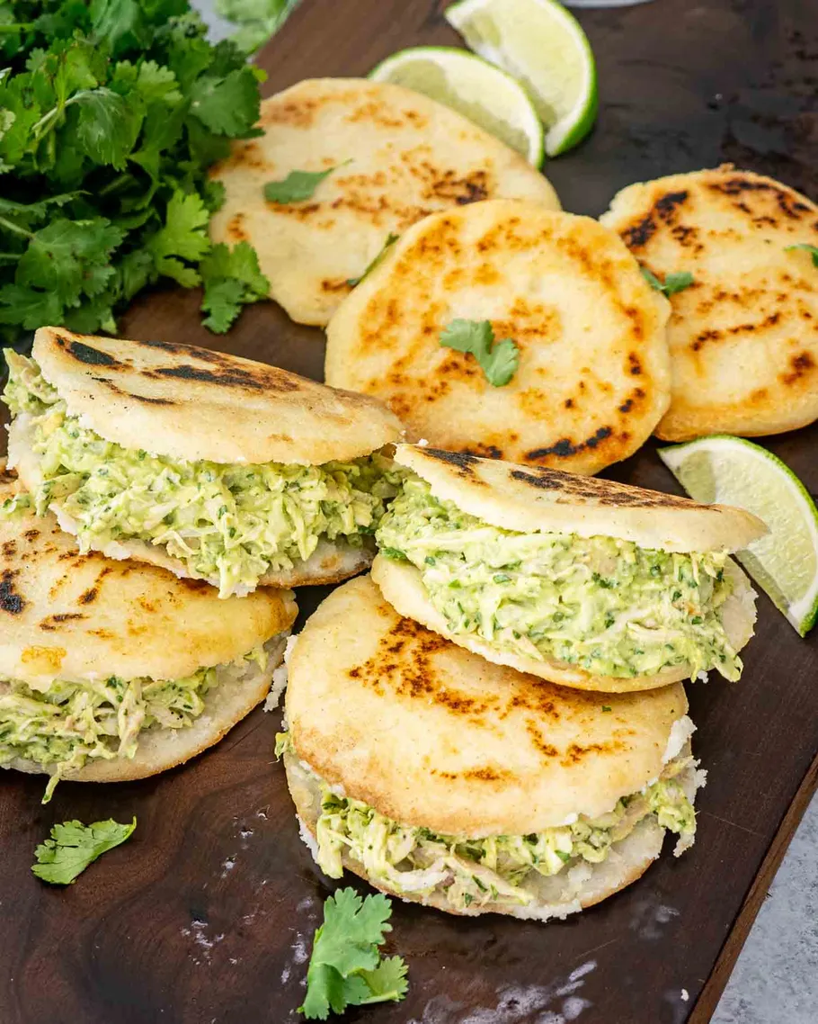 Gefüllte Arepas mit Hähnchen auf Holzbrett.