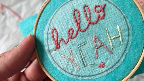 Embroidered text on blue fabric in hoop.