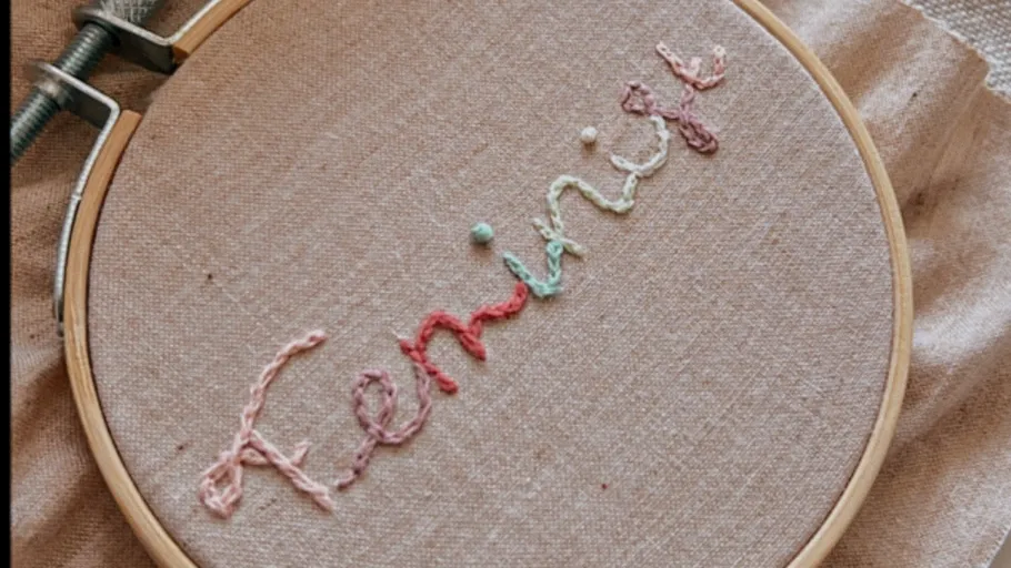 Embroidery hoop with 'feminist' text on fabric.