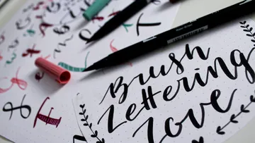 Brush pens next to calligraphy on paper.
