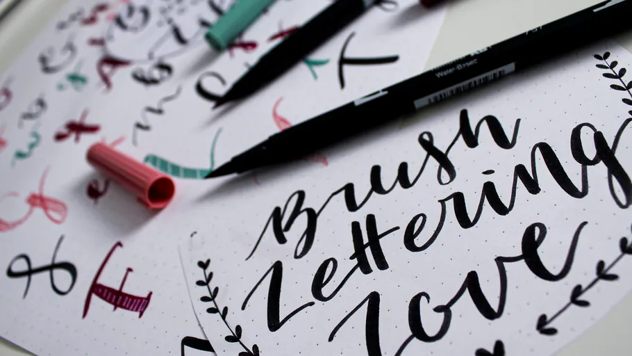 Brush pens next to calligraphy on paper.