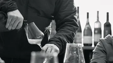 Person pouring liquid into wine glass.