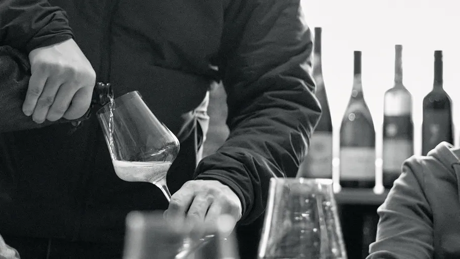Person pouring liquid into wine glass.