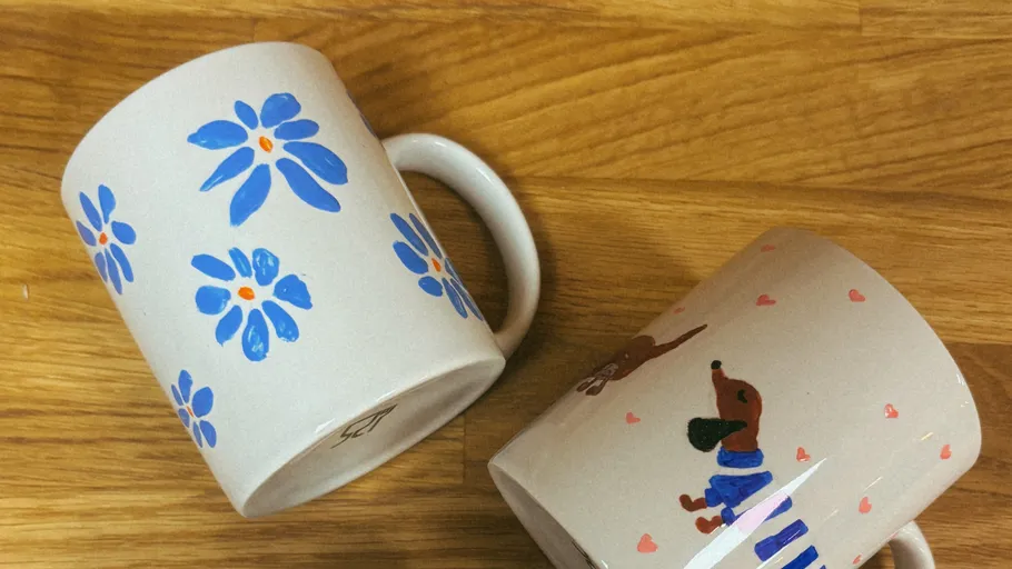 Zwei Tassen mit Blumen- und Hundemotiven auf Holz.