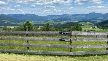 Fence with sign in scenic mountain landscape.