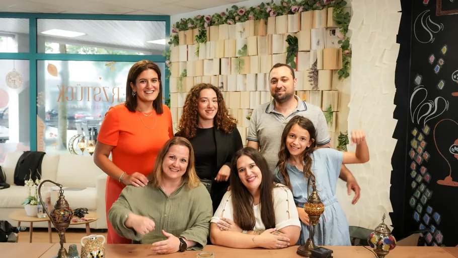 Six people smiling in a cozy indoor setting.