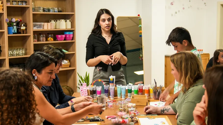 Woman instructs group in craft workshop.