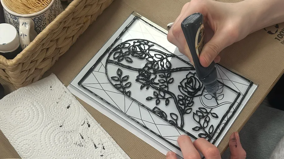 Hand trägt Farbe auf Glasmalerei-Design auf.