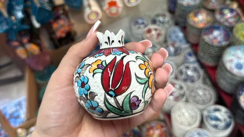 Hand hält bunte Keramikvase im Geschäft.