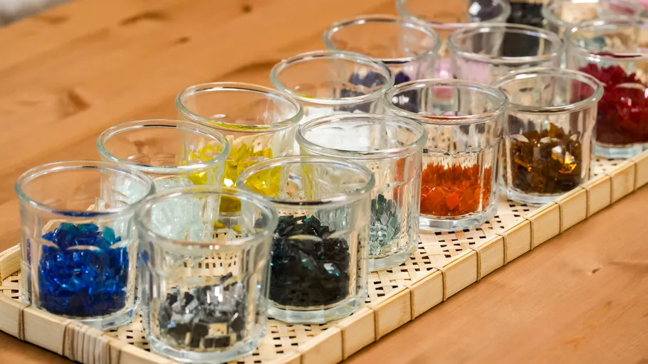 Glass cups with colorful glass pieces on table.