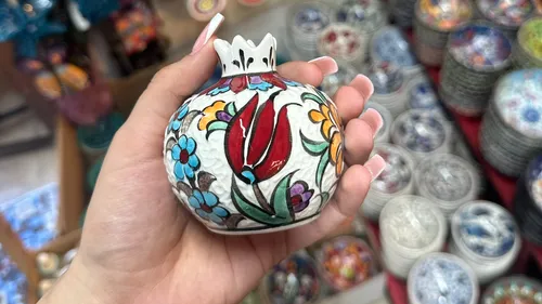 Hand hält dekorative Vase mit Blumendesign.