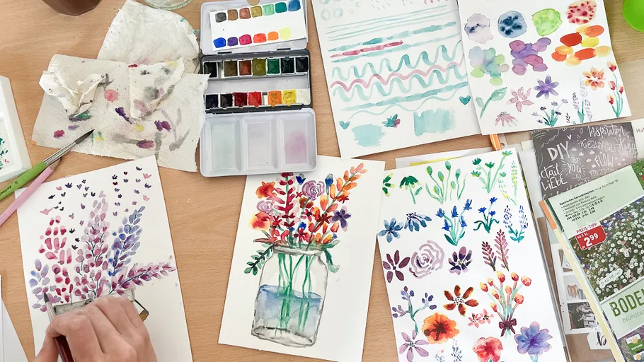 Person painting colorful floral artwork on table.