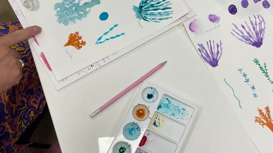 Watercolor sketches on table with paint palette.