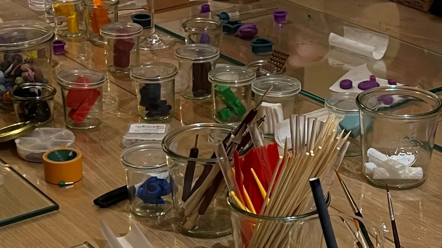 Glass jars with art supplies on table.