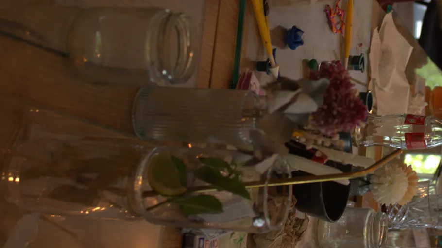 Glasgefäße mit Blumen auf unordentlichem Tisch.