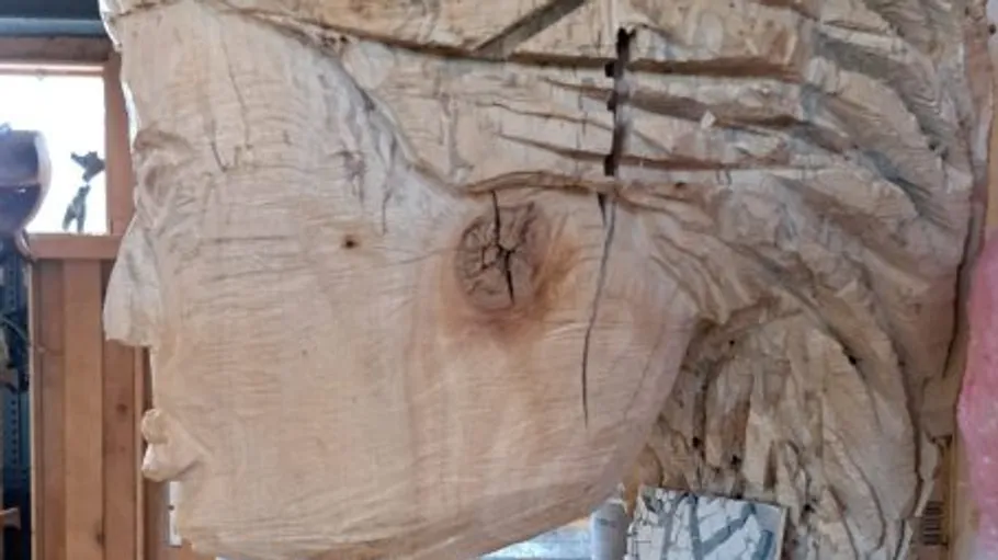 Holzskulptur eines Gesichts in Werkstatt.