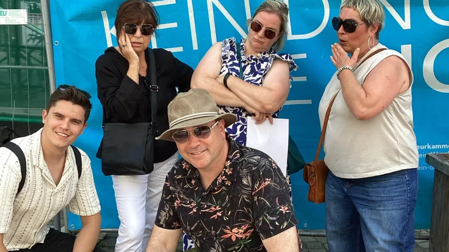 Fünf Personen posieren, blauer Hintergrund mit Text.