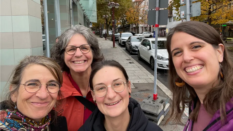 Four women smiling on a city street.