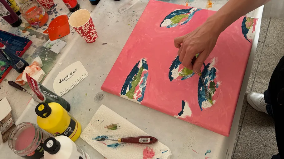 Person painting abstract art on canvas table.