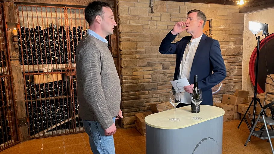 Two men talking in a wine cellar.