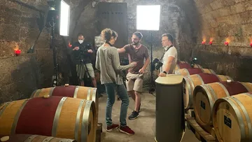 People filming in a wine cellar.