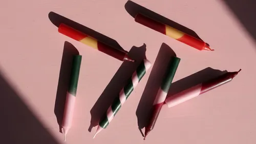 Bunte Kerzen auf pinker Oberfläche arrangiert.