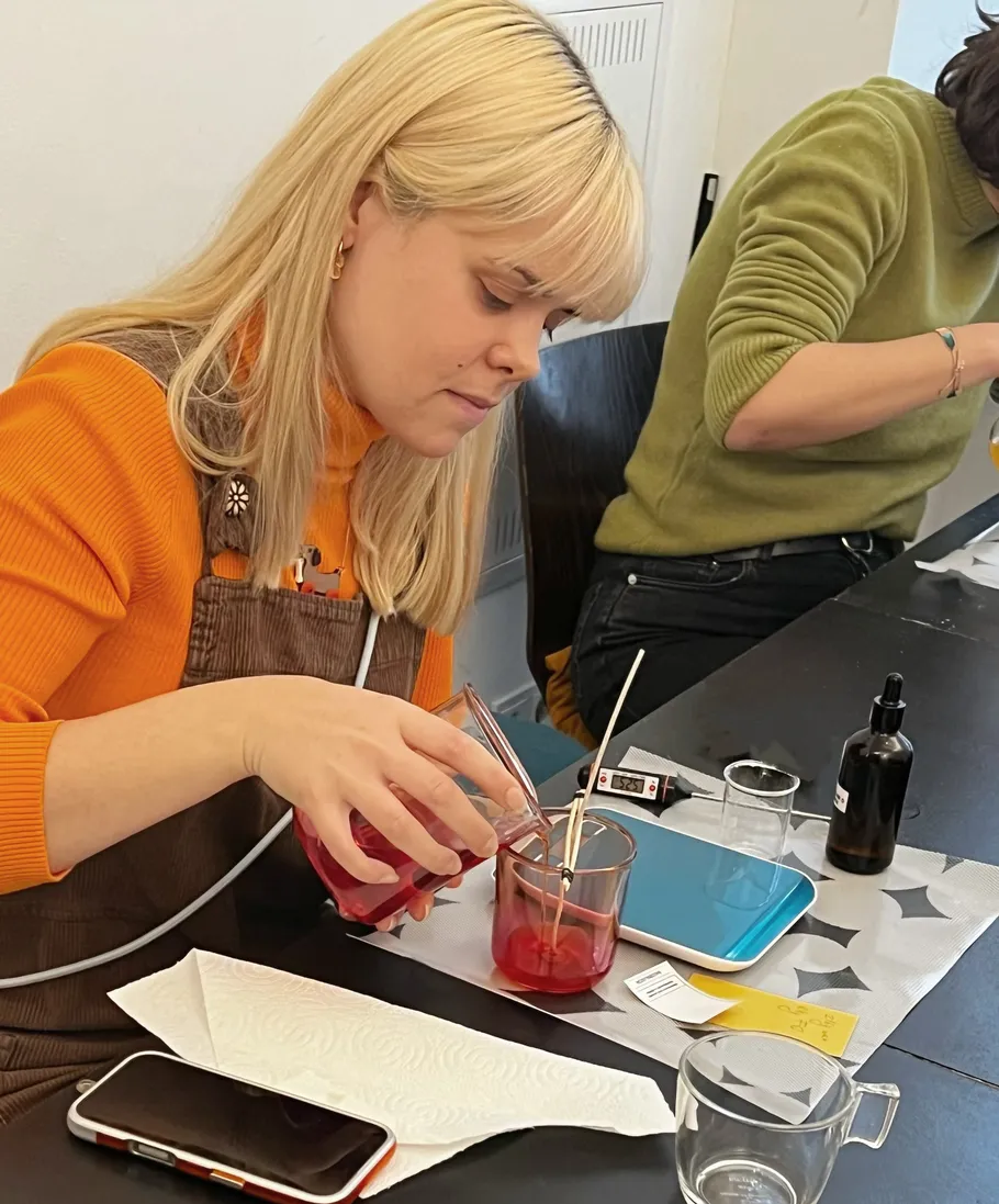 Woman pouring red liquid in glass, indoor setting.