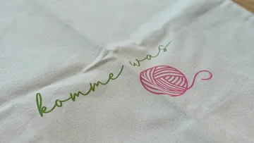 Text and yarn ball printed on fabric.