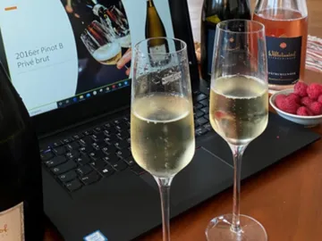 Zwei Gläser Sekt stehen auf einem Laptop, umgeben von Flaschen.
