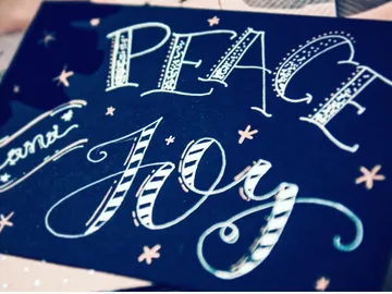Ein schwarzes Blatt mit den Worten `PEACE` und `JOY`.