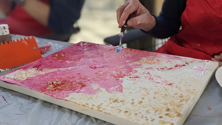 Person painting abstract art on canvas.