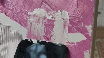 Schwarze Karte kratzt Farbe auf Leinwand ab.