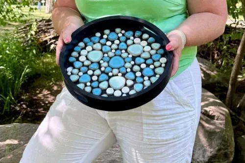 Person holding decorative round tray outdoors.