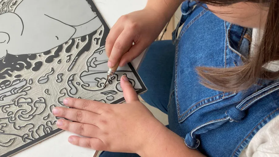 Person carving intricate design into linoleum.