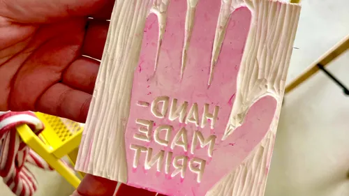 Pink hand-shaped stamp with text 'HANDMADE PRINT'.