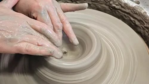 Hands shaping clay on a pottery wheel.